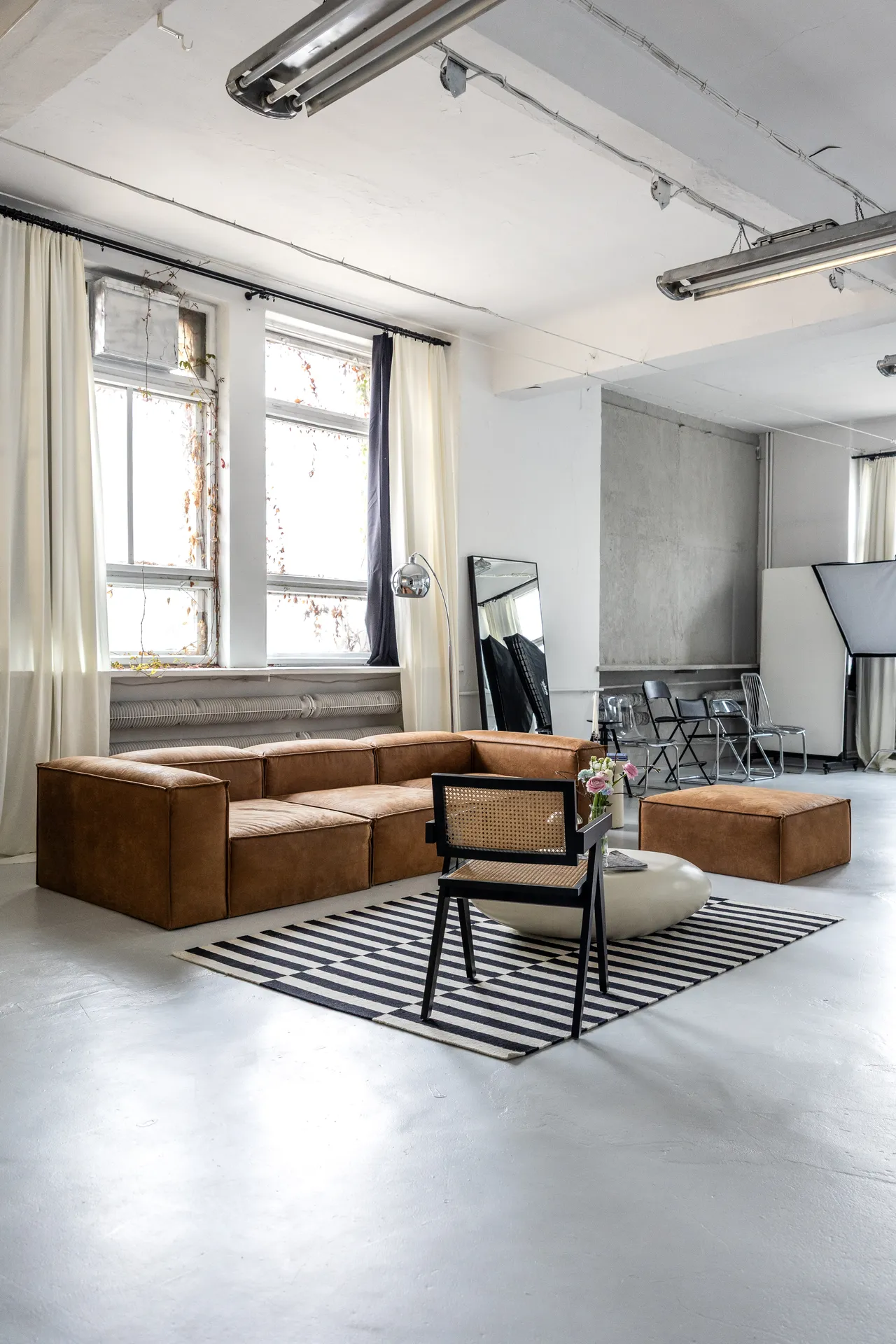 Studio fotograficzne SPOT, strefa lounge ze skórzaną sofą i czarno-białym dywanem