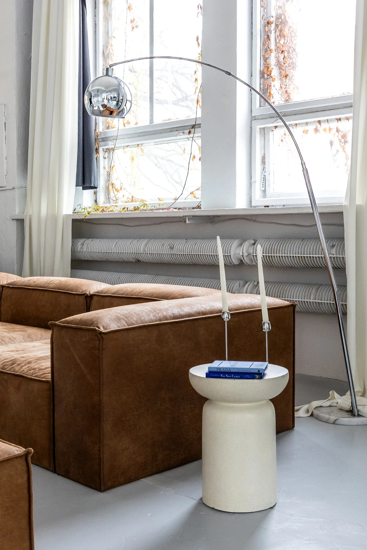 Studio SPOT Wrocław, strefa wypoczynkowa ze skórzaną sofą i chromową lampą łukową